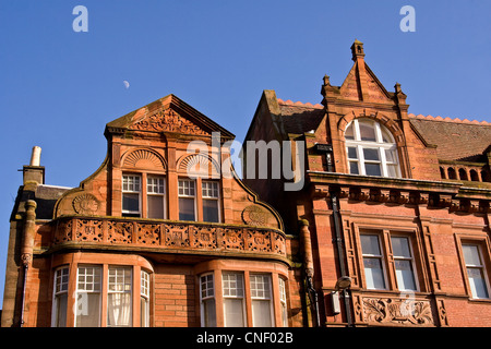 Half moon above the rooftops of a Victorian 1800`s Gothic style buildings on a bright sunny day in Dundee ,UK. Stock Photo